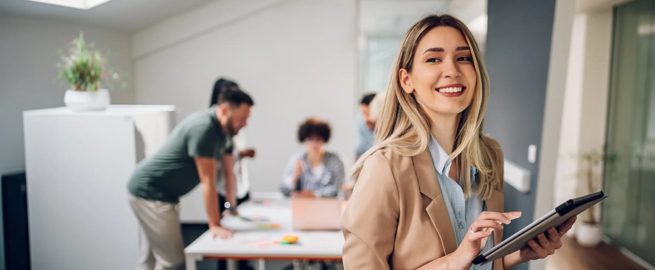 Karriere bei der LHI Leasing GmbH. Bild zeigt eine junge Frau im Büro mit zwei Personen im Hintergrund.