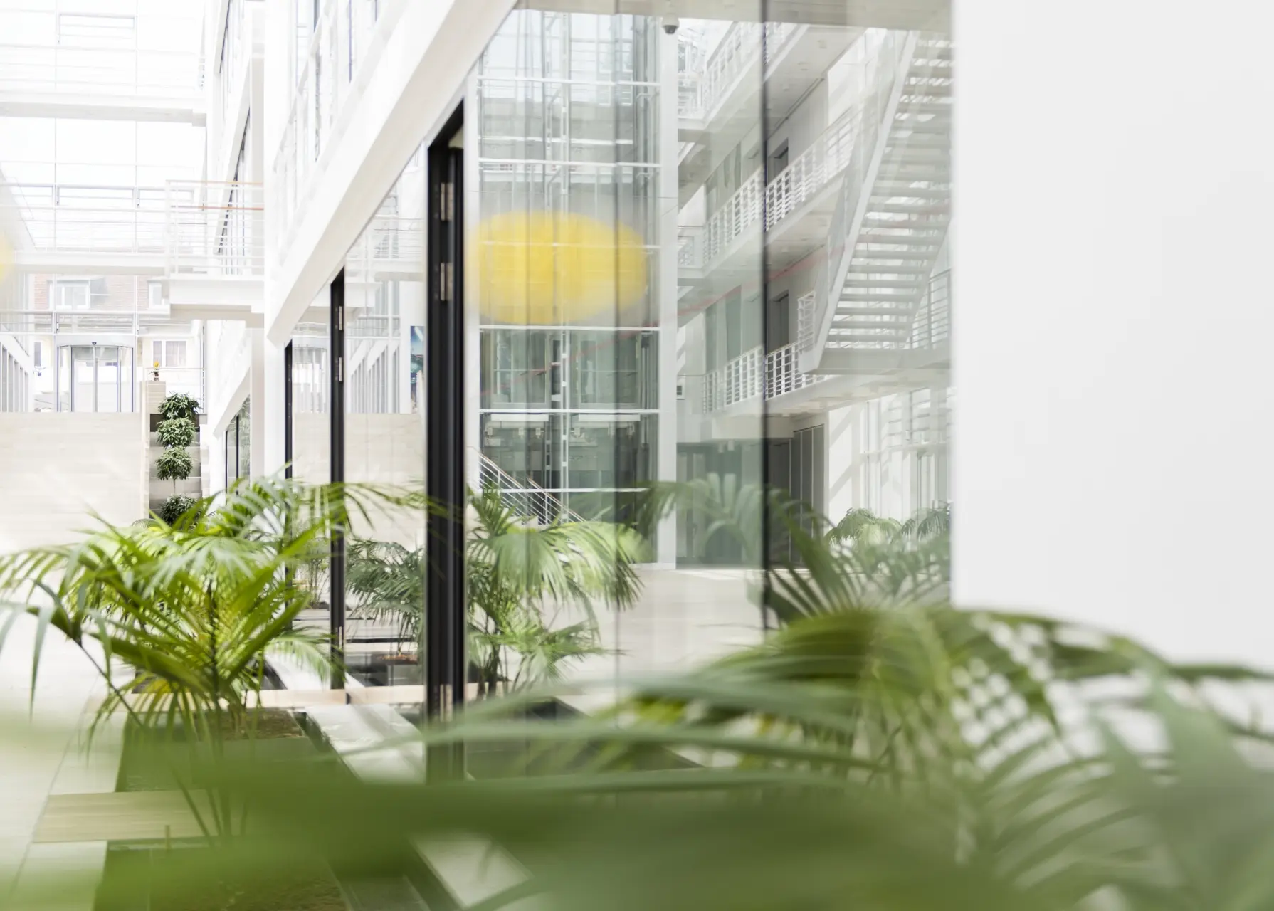 LHI Leasing GmbH. Bild zeigt ein lichtdurchflutetes Bürogebäude mit Pflanzen und verspiegelten Scheiben von innen.